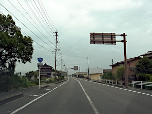 交差点前で中央線が白実線になっている、左の歩道に国道標識が立っている